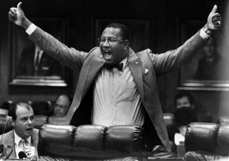 Black and White photo of Dr. Reddick with his arms out wide shouting in professional attire.