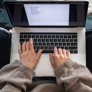 Close-up of hands typing on a laptop keyboard, viewed from above.