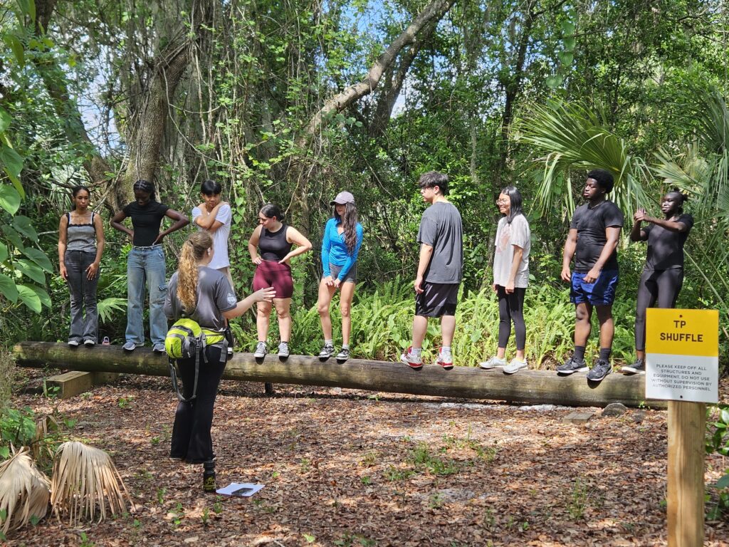 DSI students doing a team builder where they try to orientate themselves in a certain order on a log