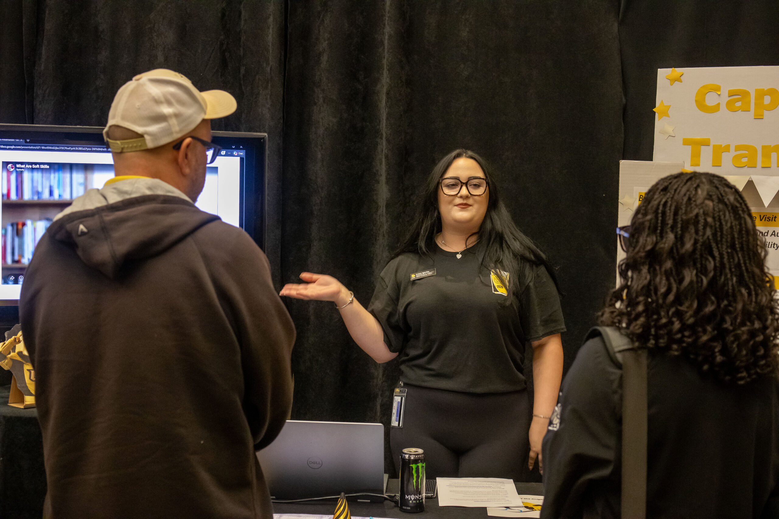 The facilitator for Captioning and Transcript station presenting to two attendees
