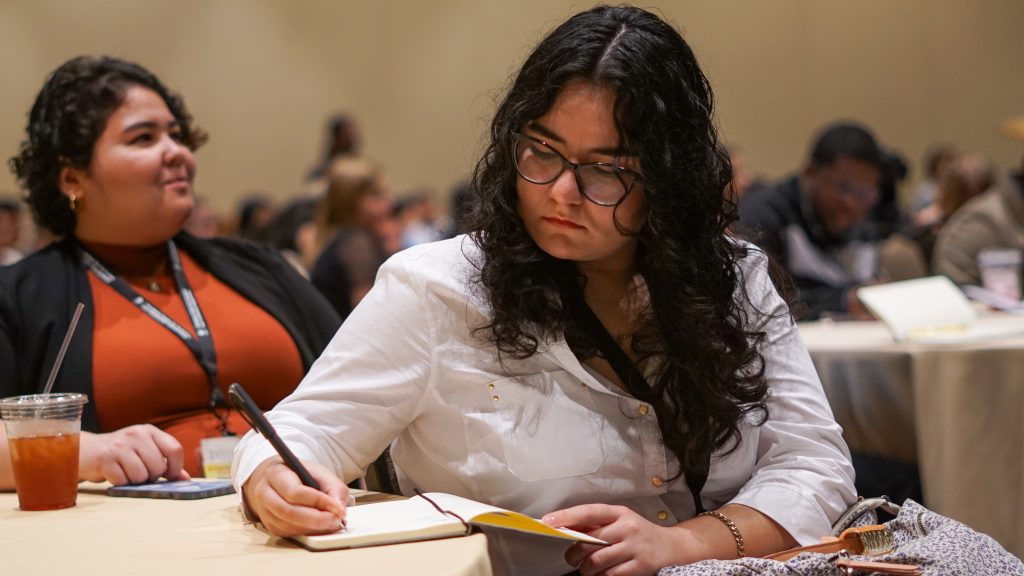 A student taking notes during a keynote