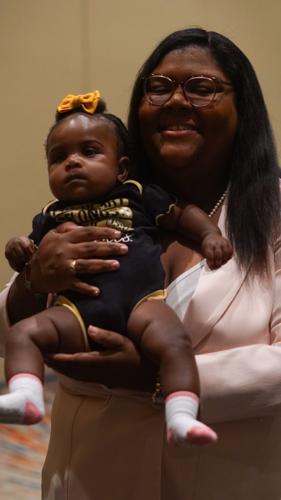 A panelist and her baby daughter wearing a UCF outfit and bow