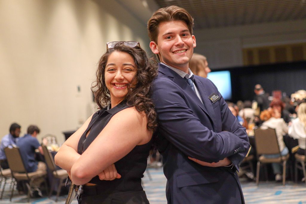 Two students back-to-back posing in professional attire