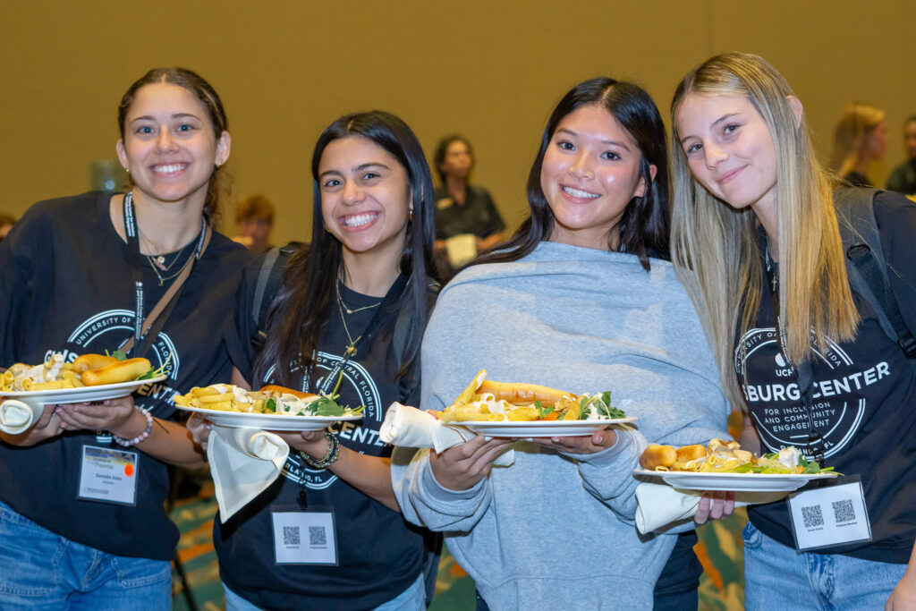 Female students posing and holding plates of food