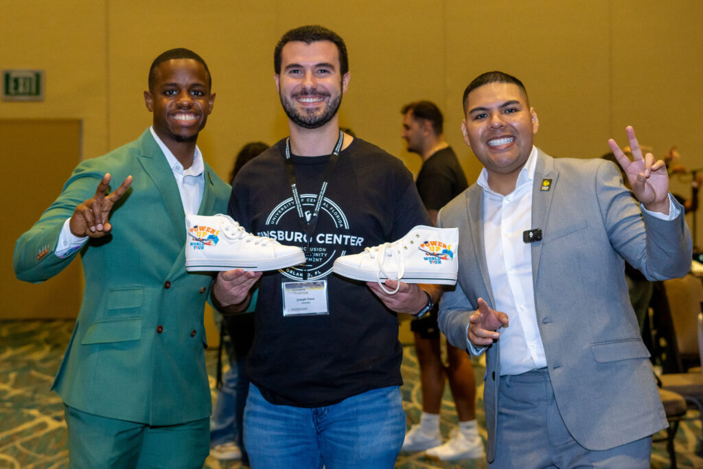 A student with keynote speakers holding up shoes he won