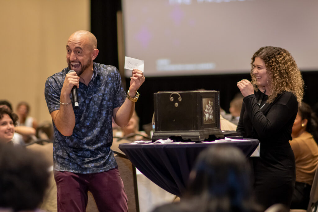 Keynote speaker holding an index card and a student laughing