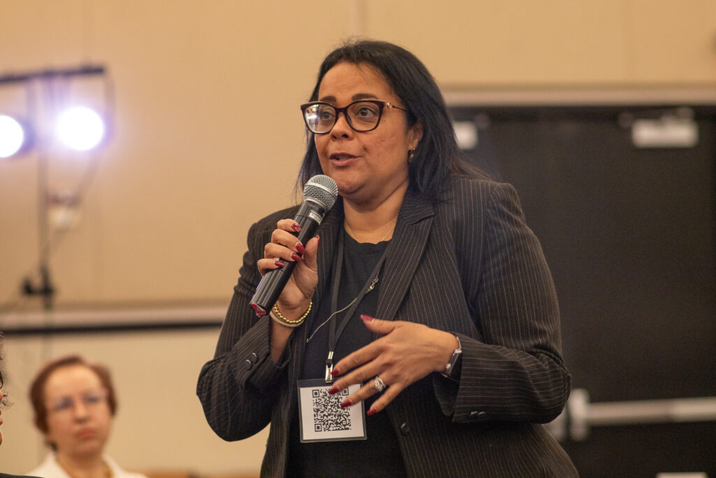 A woman with dark hair using a microphone to ask a question