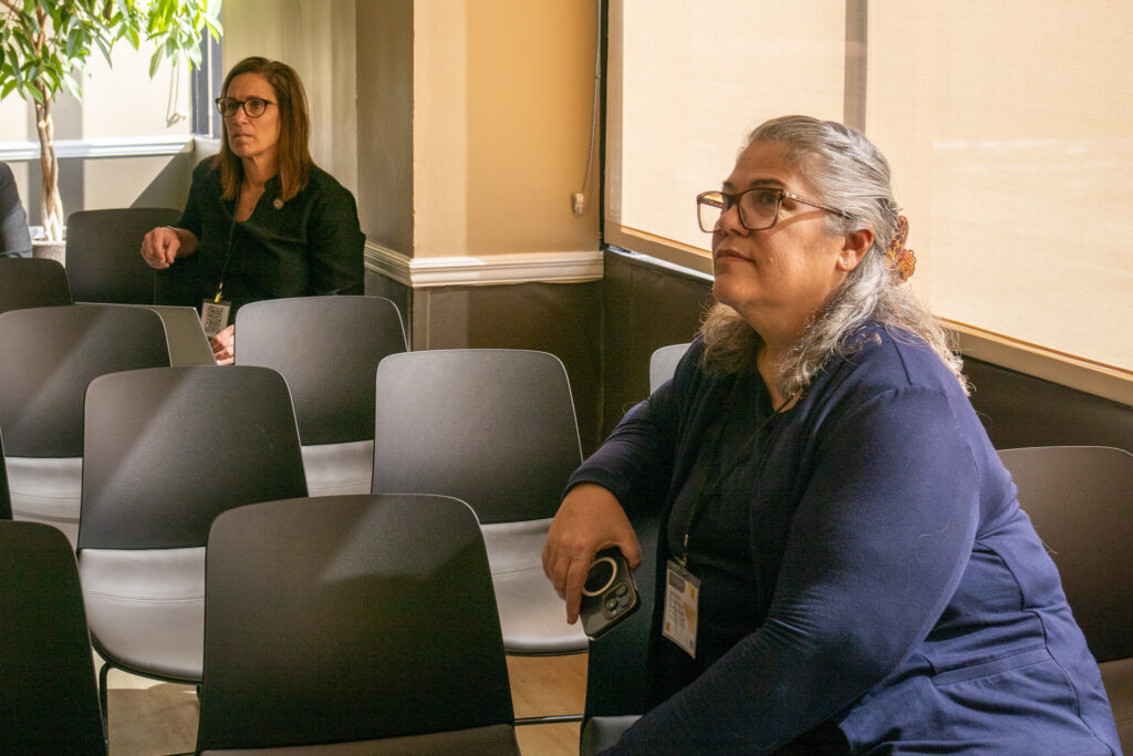 Two attendees sitting listening to a presenter