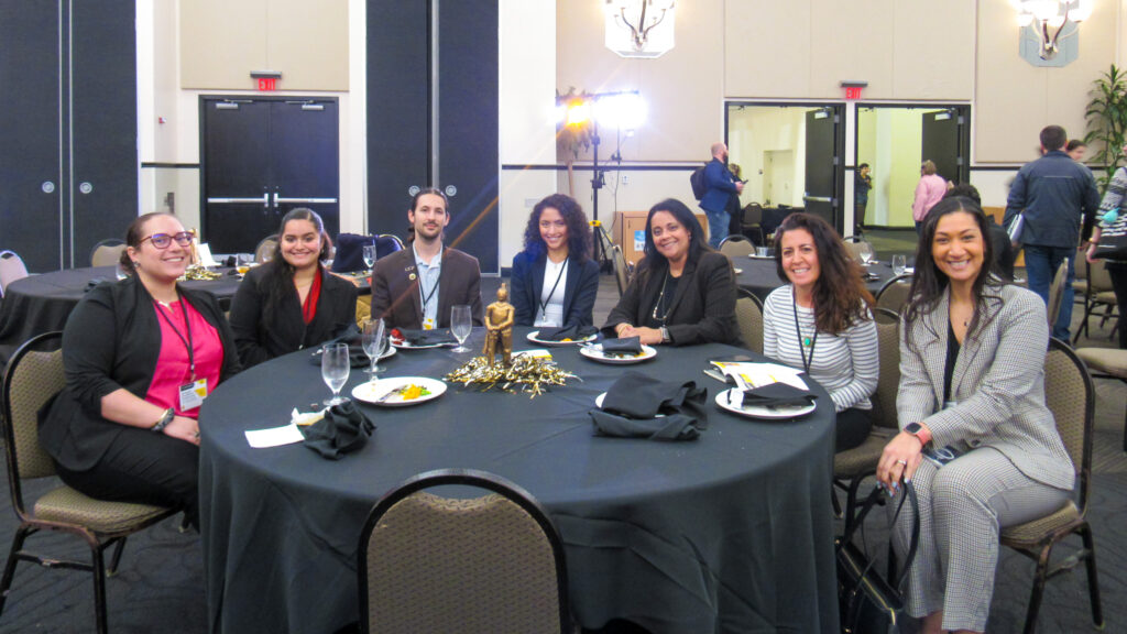 A team of staff members posing for a photo around a table